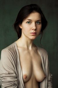 Woman with dark hair pulled back wears an open beige cardigan against a deep green backdrop.