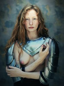 Woman with long auburn hair wearing polished steel shoulder armour over bare chest, against a textured blue-grey painted background.