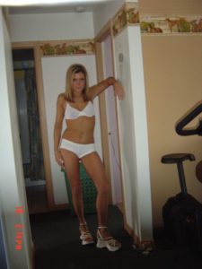 Woman in white bra and briefs standing in narrow hallway by doorway